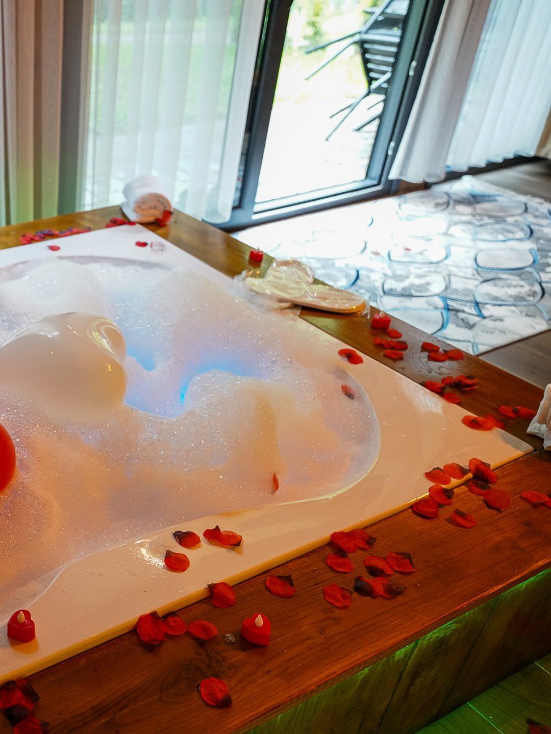 Una bañera de hidromasaje con pétalos de rosa y velas.