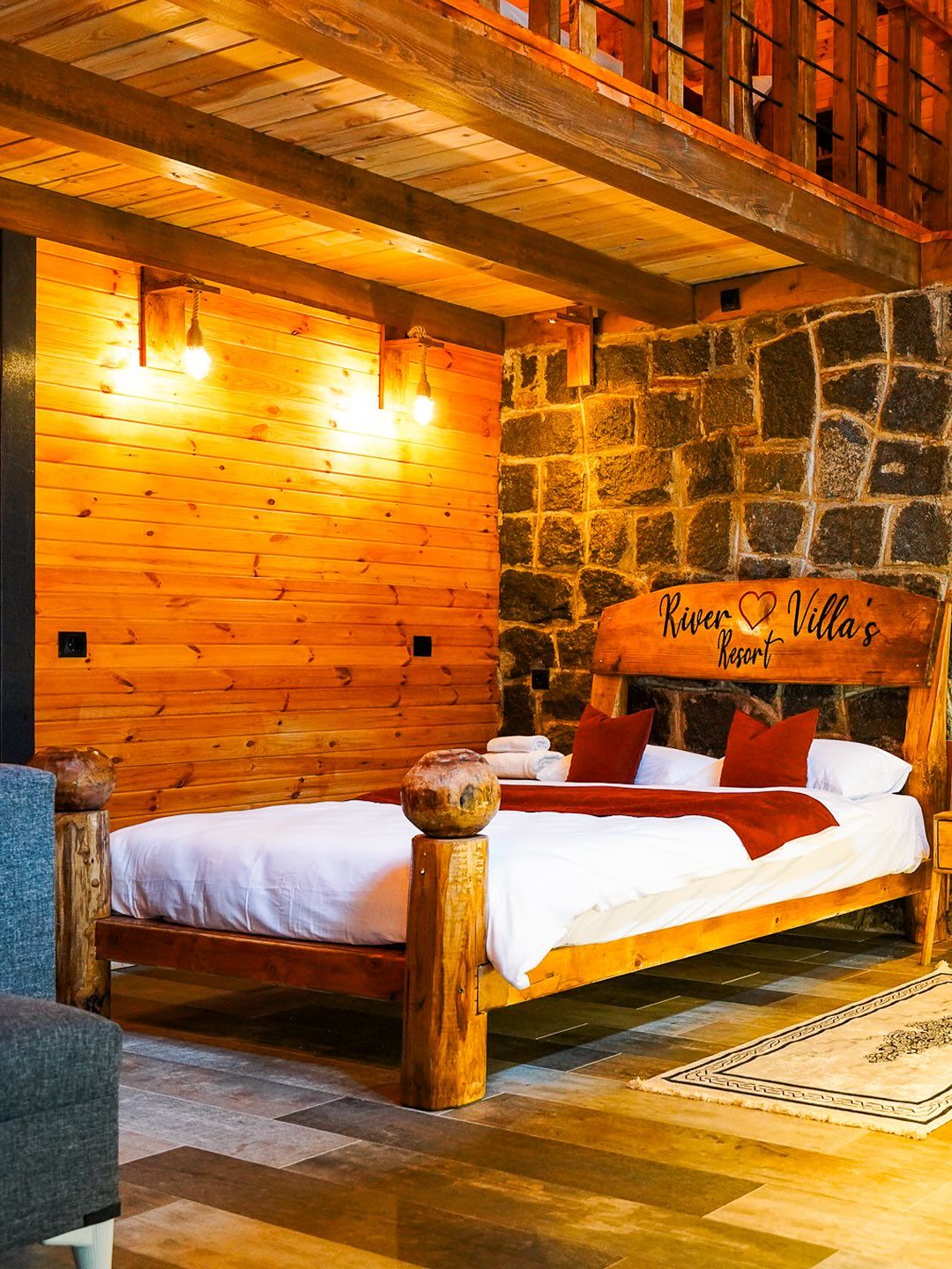 A wooden bed with a stone wall backdrop and a sign reading 'River Villa's Resort'.