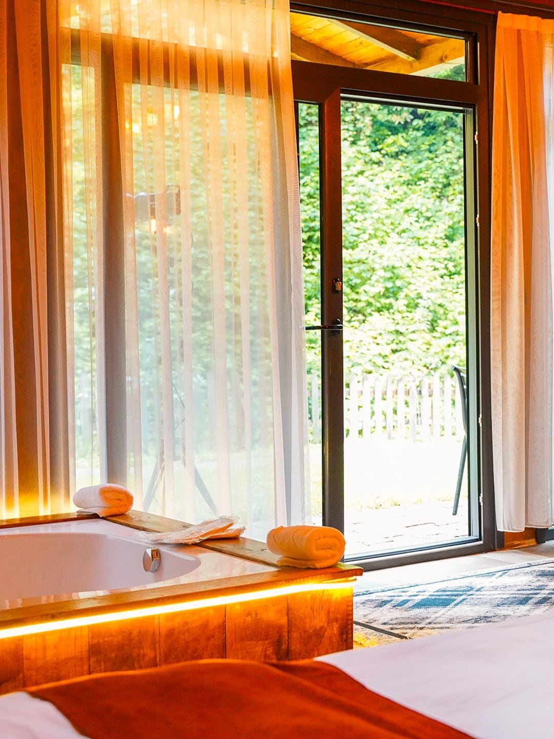 Une salle de bain avec une baignoire, une serviette et une fenêtre avec des rideaux.
