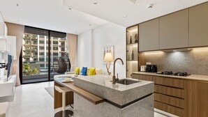Une cuisine moderne dotée d’un îlot central, d’un coin repas avec un canapé et une table, et d’une grande fenêtre donnant sur un paysage urbain.