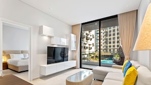 Une chambre d’hôtel moderne équipée d’un lit, d’une télévision, d’un canapé et d’une table basse en verre.
