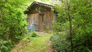 A rustic wooden cabin surrounded by dense greenery. - Atelier du Moulin all in wood classified 2 * for 2 to 4 pers - on the banks of the torrent (Aubusson-d'Auvergne)
