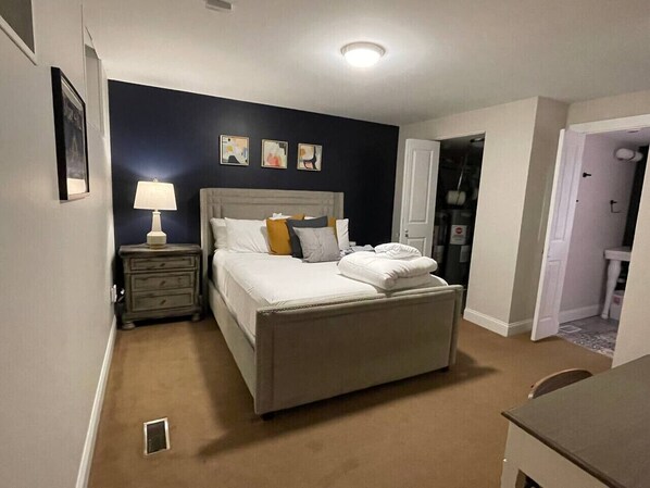 A bedroom with a bed, bedside table, lamp, and artwork on the wall.