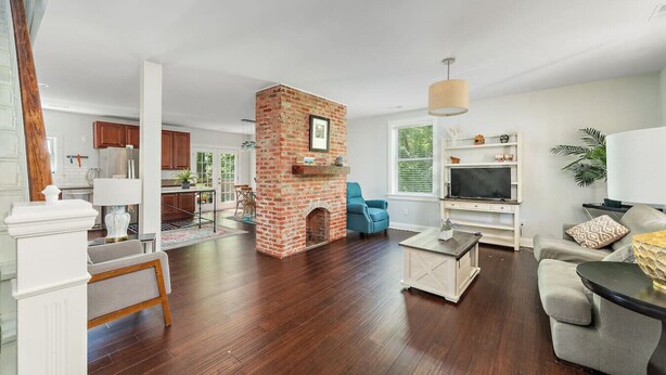 A spacious living room with hardwood flooring, a brick fireplace, a television, and a comfortable seating area. - 2 Apts w/ Terrace-OTR, Findlay Market, Rhinegeist (Cincinnati)
