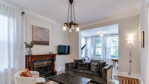 Ein Wohnzimmer mit Kamin, einer großen Couch, einem Couchtisch und einem an der Wand montierten Fernseher.