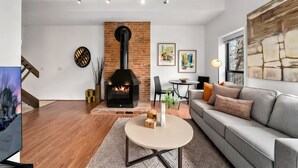 A modern living room with a fireplace, a sofa, a coffee table, and artwork on the walls. - 1BR Condo Steps to the Monastery, Cafes, and More (Cincinnati)