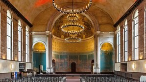 An interior with a large arched ceiling, multiple chandeliers, and rows of chairs arranged for an audience. - 1BR Condo Steps to the Monastery, Cafes, and More (Cincinnati)