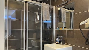 Une salle de bain moderne avec une douche à parois de verre, un lavabo blanc et un miroir au-dessus.