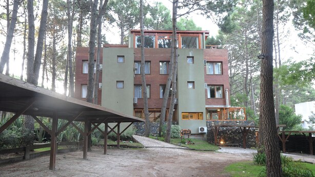 Un immeuble à plusieurs étages, doté d’une façade en briques, entouré de grands arbres.
