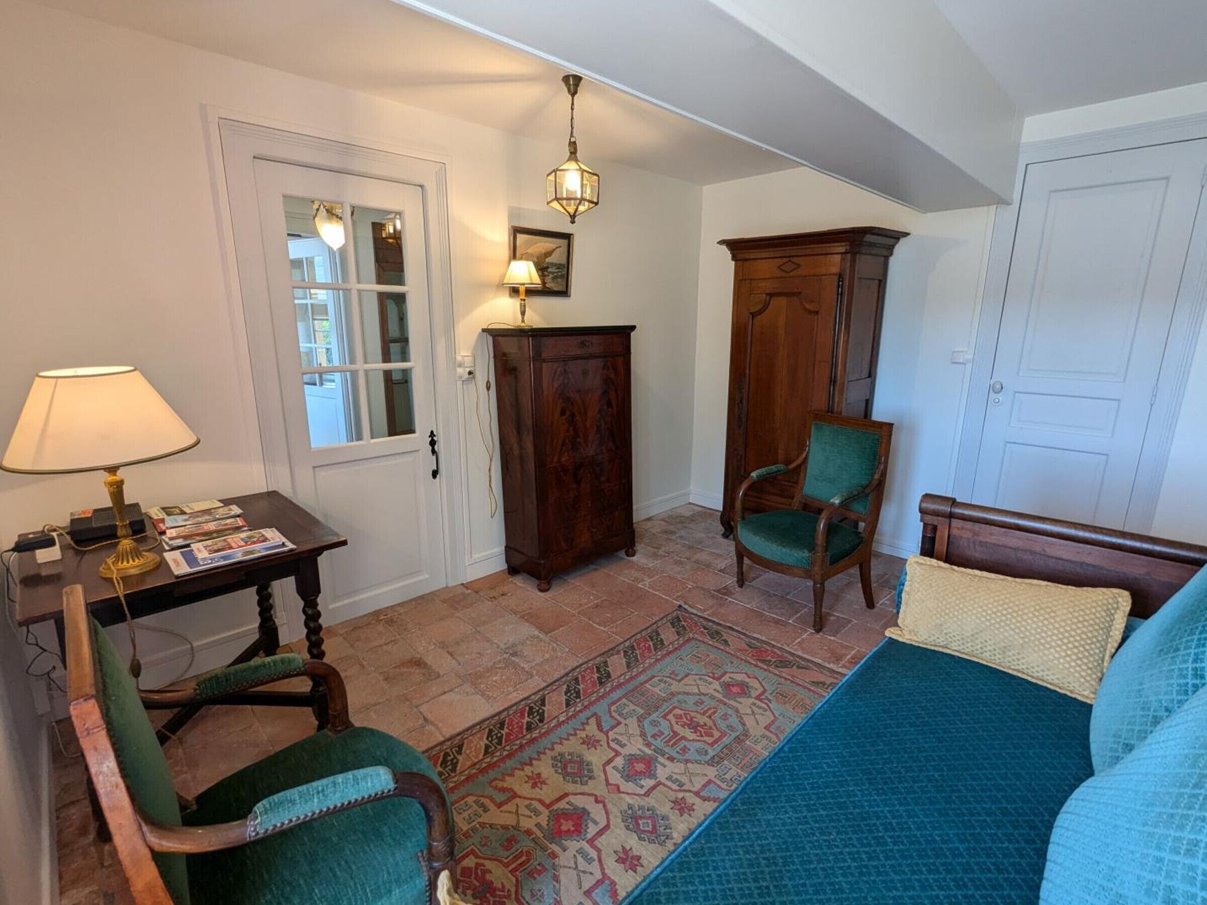 A room with a bed, a chair, a table with a lamp, a cabinet, and a rug.