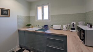 Eine moderne Küche mit Spüle, Arbeitsfläche und Geräten, darunter ein Toaster, ein Wasserkocher und eine Kaffeemaschine.