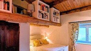 A bedroom with a bed, wooden ceiling, bookshelves, and a window with curtains. - Couple's Retreat in Vineyard House with Terrace (Tailhac)