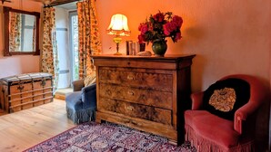A cozy room with a wooden dresser, a chair, a lamp, and a vase of flowers. - Couple's Retreat in Vineyard House with Terrace (Tailhac)
