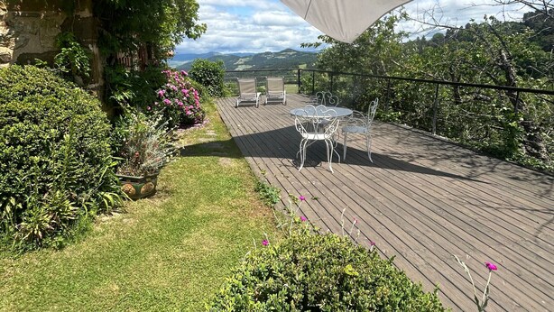 A wooden deck with outdoor furniture, surrounded by lush greenery and a scenic view. - Couple's Retreat in Vineyard House with Terrace (Tailhac)