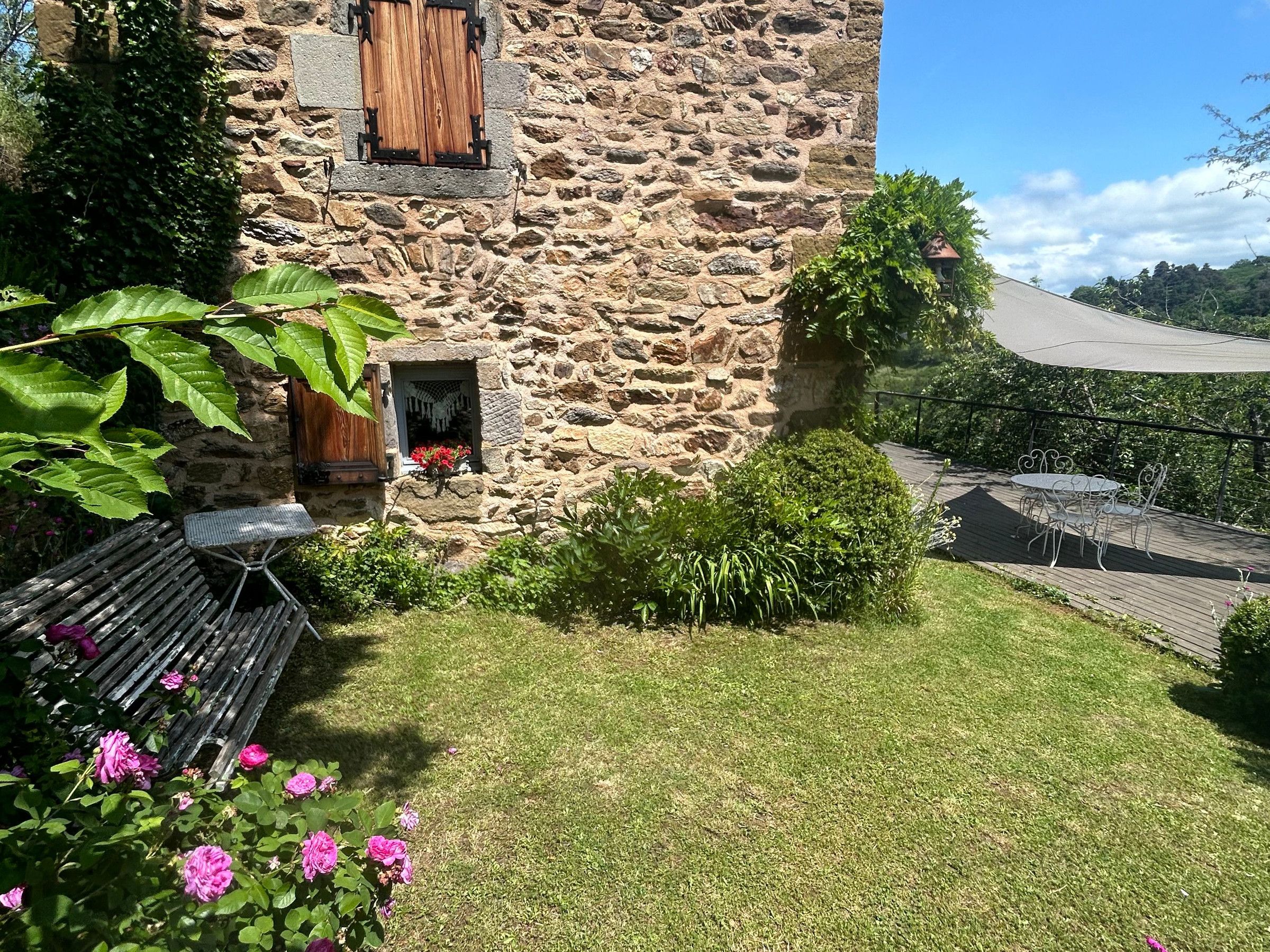 A stone building with a wooden window, a small door, and a balcony with a table and chairs.