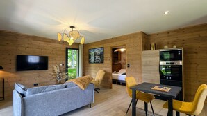 Una sala de estar moderna con un sofá gris, sillas amarillas, una mesa de comedor, un televisor y una pared de madera.