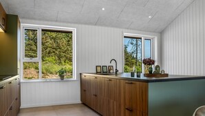 Een moderne keuken met houten kastjes, een zwart aanrecht en een raam met uitzicht op groen.