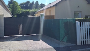 A residential area with a gated entrance, a white picket fence, and a building with a light-colored exterior. - Detached house with enclosed garden and electric charging in Gacé (Gacé)