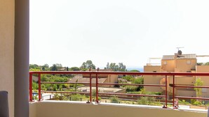 A balcony with a red railing overlooking a residential area with houses and greenery. - Bright apartment with large terrace and pool, Le Lavandou (Le Lavandou)
