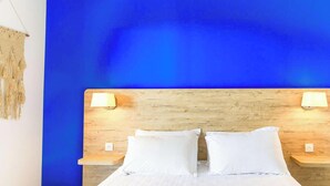 Un lit avec une tête de lit en bois, deux lampes de chevet et un mur bleu.