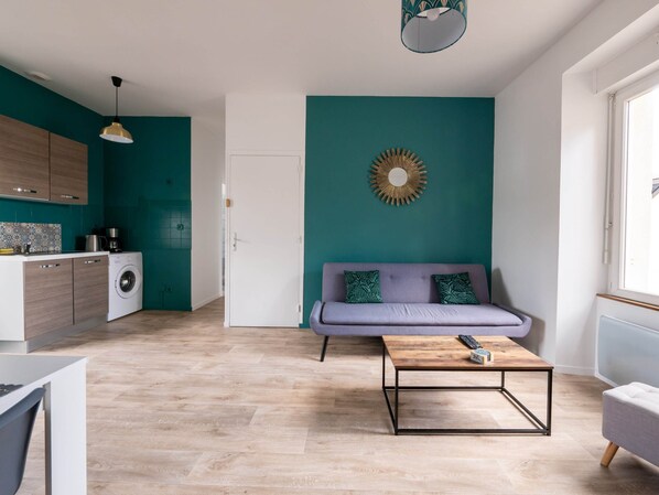 A modern apartment with a kitchen, a sofa, and a coffee table.
