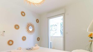 A hotel room with a bed, a wall-mounted mirror, and a window with a view of trees.