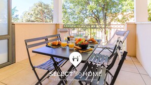 A balcony with a table set for breakfast, including croissants, fruit, and orange juice.