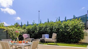 An outdoor patio area with a table set for breakfast, chairs, and a hedge in the background. - 2-room apartment with terrace, pool and pets allowed at La Favière (Bormes-les-Mimosas)