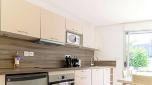 A modern kitchen with light-colored cabinets, a built-in microwave, and a coffee machine. - 2-room apartment with terrace, pool and pets allowed at La Favière (Bormes-les-Mimosas)