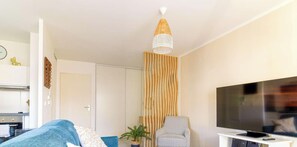 A modern living room with a sofa, a chair, a TV, and a decorative wall panel.