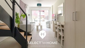 Un interior moderno con una escalera, un sofá, un comedor y vistas al exterior.