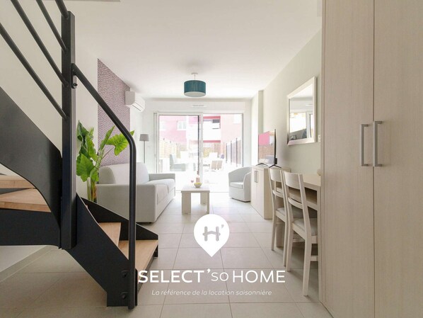 Un intérieur moderne comprenant un escalier, un canapé, un coin repas et une vue sur l’extérieur.