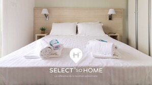 Habitación de hotel con cama, dos mesitas de noche y una lámpara de pared.