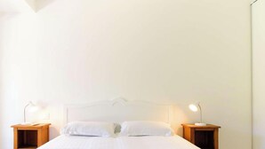 A bedroom with a bed, two bedside tables, and two lamps.