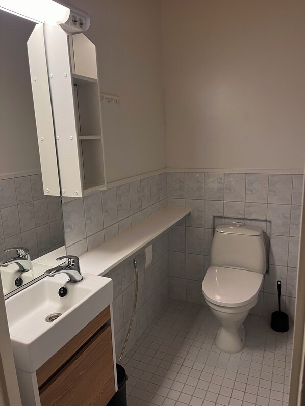 Un baño con lavamanos blanco, espejo y retrete.