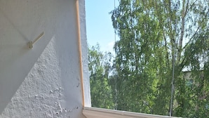 Een balkon met een tafel, stoelen, een leuning en uitzicht op bomen en gebouwen.