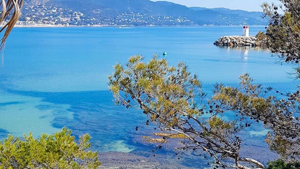 A coastal landscape with clear water, rocky shore, and distant buildings. - Modern T3 with Lovely Terrace in Bormes-les-Mimosas (Bormes-les-Mimosas)