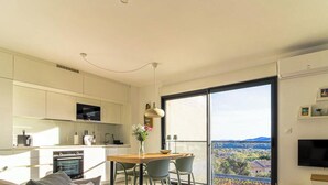 A modern kitchen with a dining area, a TV, and a balcony with a view. - Modern T3 with Lovely Terrace in Bormes-les-Mimosas (Bormes-les-Mimosas)