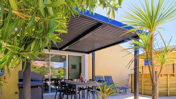 Une terrasse extérieure équipée d’un barbecue, d’une table à manger, de chaises et d’une clôture en bois.