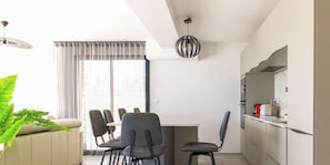 Uma cozinha moderna com área de refeições, um sofá e uma janela grande com cortinas.