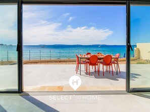 A seaside view from a modern home with a dining area, a pool, and a clear sky. - Idyllic beachfront stay in Lavandou (Le Lavandou)