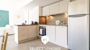 A modern kitchen with white cabinets, a stainless steel refrigerator, and a built-in oven.
