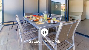 An outdoor dining area with a table set for breakfast, including croissants, fruits, and beverages.