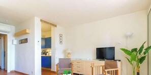 Um espaço compacto com cozinha compacta, televisão, escrivaninha e uma cadeira.