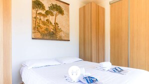 Une chambre à coucher avec un lit, un tableau représentant des arbres et une armoire en bois.