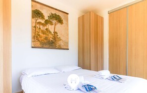 Une chambre à coucher avec un lit, un tableau représentant des arbres et une armoire en bois.