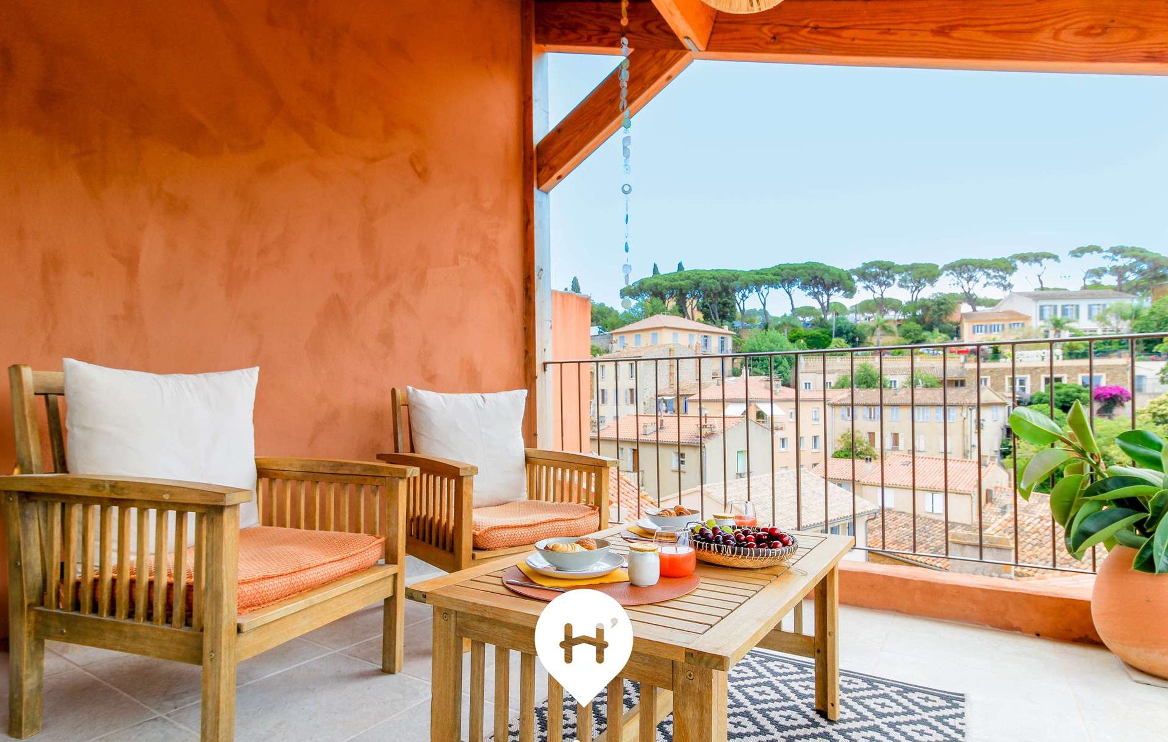 Un balcone con mobili in legno, un tavolo imbandito e vista su edifici e alberi.