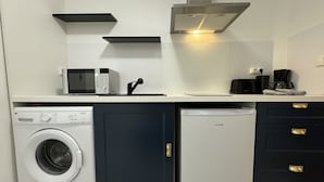 A compact kitchen with a washing machine, a small refrigerator, a microwave, and a coffee maker. - Apartment in Le Mans Near 24 Hours Circuit (Le Mans)