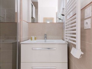 A modern bathroom with a white vanity, a mirror, and a towel rack.