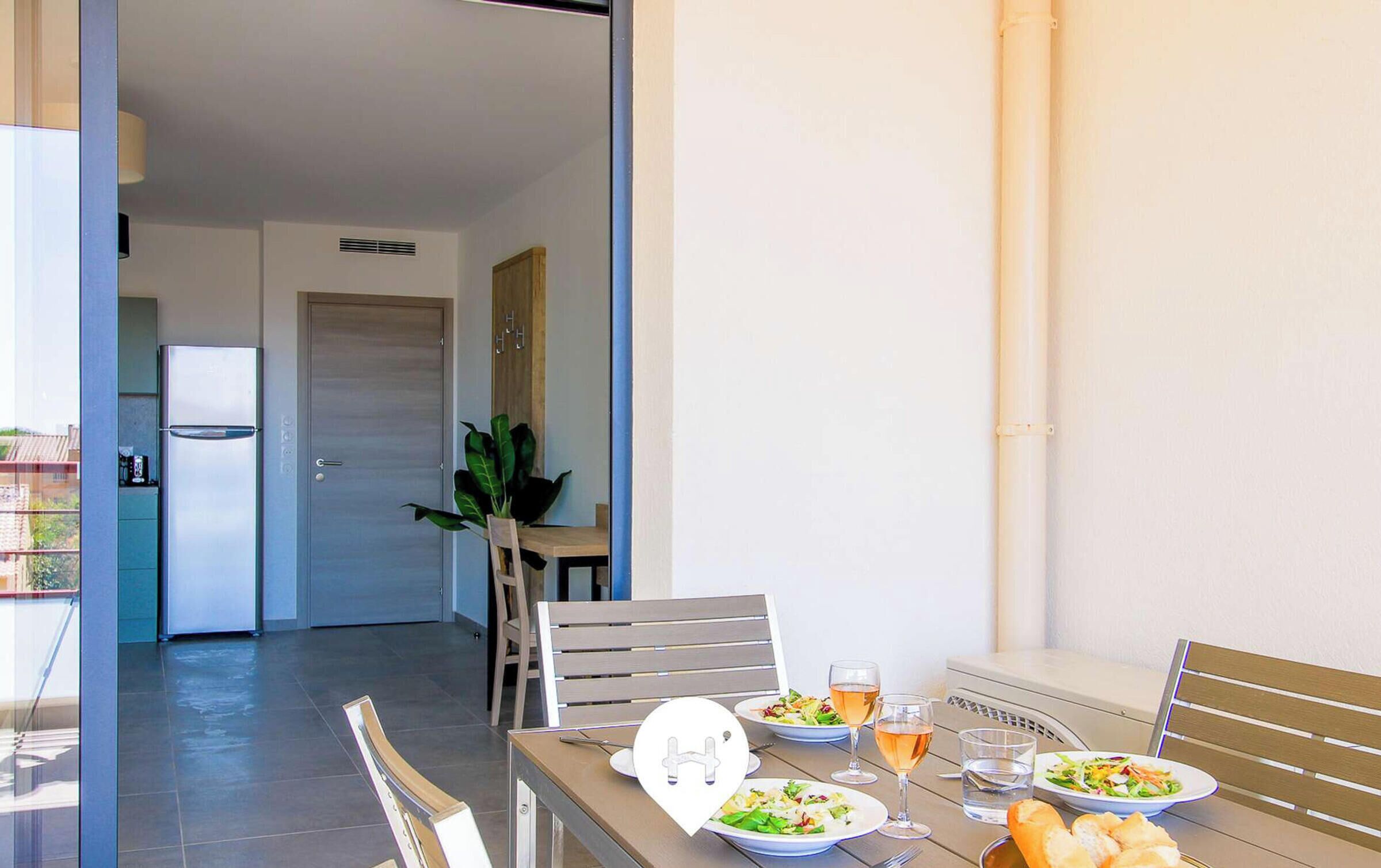 A dining area with a table set for two, featuring plates of food, glasses of wine, and bread.